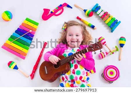 Child with music instruments. Musical education for kids. Colorful wooden art toys for kids. Little girl playing music. Kid with xylophone, guitar, flute.