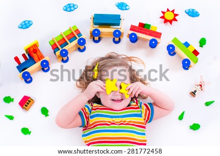 Child playing with wooden train. Toy railroad for kids. Toddler kid at day care. Educational toys for preschool and kindergarten child. Little girl at daycare.