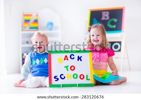 Kids at preschool. Two children drawing and painting at kindergarten. Boy and girl happy to go back to school. Toddler kid and baby learn letters at child care. Class room with chalkboard and abacus