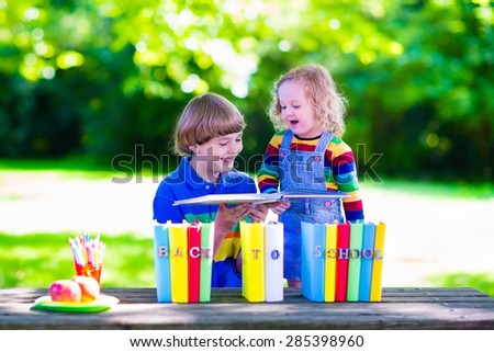 Child in school. Smart teenager student boy and preschooler girl studying and learning outdoors, reading books and having apple for healthy snack. Kids happy to be back to school. Children in a class.