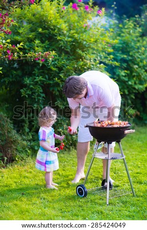 Father and child grilling meat. Family camping and enjoying BBQ. Dad and daughter at barbecue preparing steaks and sausages. Parents and kids eating grill meal outdoors. Garden fun for children.