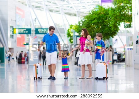 Family traveling with kids. Parents with children at international airport with luggage. Mother and father hold baby, toddler girl and boy flying by airplane. Travel with child for summer vacation.