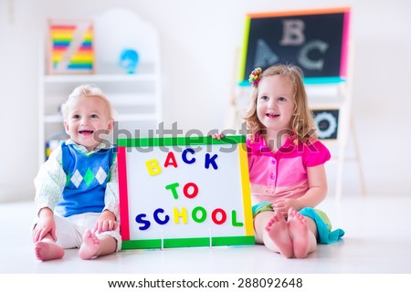 Kids at preschool. Two children drawing and painting at kindergarten. Boy and girl happy to go back to school. Toddler kid and baby learn letters at child care. Class room with chalkboard and abacus