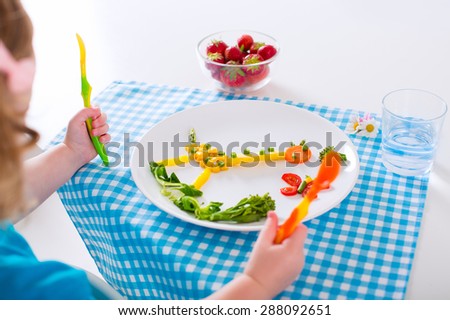 Healthy vegetarian lunch for little kids. Kid meal. Vegetable and fruit served as animals, corn, broccoli, carrot, strawberry helping child to learn eating right and clean, children hands with spoon