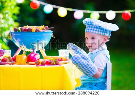 Children grilling meat. Family camping and enjoying BBQ. Little boy at barbecue preparing steaks, kebab and corn. Kids eating grill and healthy vegetable meal outdoors. Garden party for toddler child