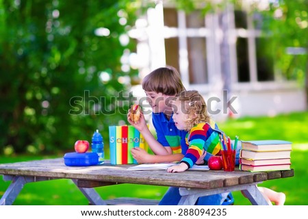 Child in school. Smart teenager student boy and preschooler girl studying and learning outdoors, reading books and having apple for healthy snack. Kids happy to be back to school. Children in a class.