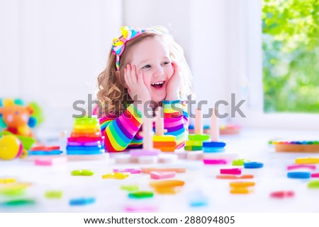 Preschooler child playing with colorful toy blocks. Kids play with educational wooden toys at kindergarten or day care. Preschool children build tower with wood block. Toddler kid in nursery.