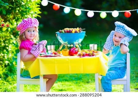 Children grilling meat. Family camping and enjoying BBQ. Brother and sister at barbecue preparing steaks and sausages. Kids eating grill and healthy vegetable meal outdoors. Garden party for child.