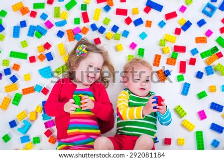 Child playing with colorful toys. Little girl and baby boy with educational toy blocks. Children play at day care or preschool. Mess in kids room. View from above.