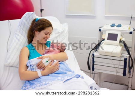 Mother giving birth to a baby. Newborn baby in delivery room. Mom holding her new born child after labor. Female pregnant patient in a modern hospital. Parent and infant first moments of bonding.