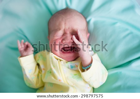 Newborn baby boy in bed. New born child sleeping on a green blanket. Children sleep. Bedding for kids. Infant napping in bed. Healthy little kid shortly after birth. Tired baby yawning.