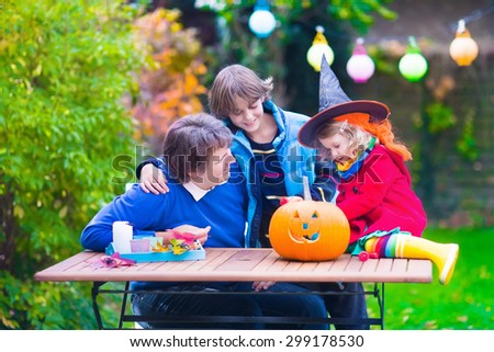 Family carving pumpkin at Halloween. Dressed up child trick or treating. Kids and parents trick or treat. Child in witch costume playing in autumn park. Toddler kid with jack-o-lantern.