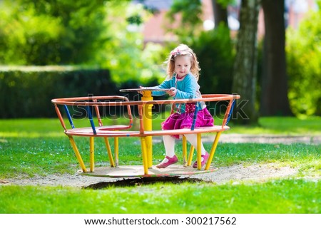 Little girl on a playground. Child playing outdoors in summer. Kids play on school yard. Happy kid in kindergarten or preschool. Children having fun at daycare play ground. Toddler on a slide.