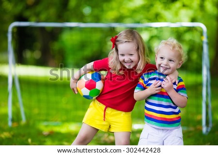 Two happy children playing European football outdoors in school yard. Kids play soccer. Active sport for preschool child. Ball game for young kid team. Boy and girl score a goal in football match.