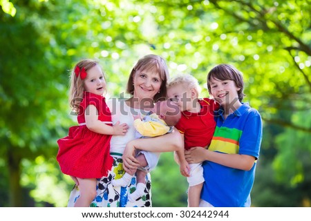 Mother and children play in a park. Woman with newborn baby, little girl, toddler and teenager boy. Siblings with big age difference. Kids with large age gap. Young grandmother with grandchildren.
