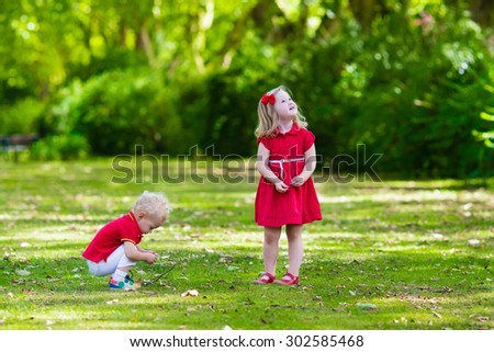 Children playing in the garden. Toddler kid and little baby play outdoors in summer. Girl and boy with golden maple leaf in fall forest. Child playing with autumn leaf. Outdoor fun for kids.