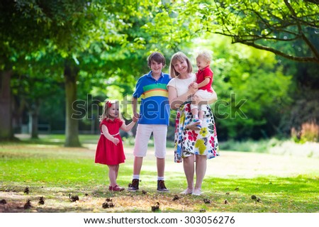 Grandmother and grandchildren enjoying picnic in a park. Grandma playing with children in a sunny autumn forest. Summer outdoor fun in the garden. Grandparents and kids on a meadow.
