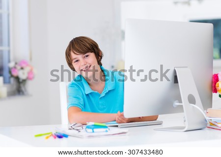 School boy working on personal computer at home. Student doing homework using modern pc in classroom. Kids studying with digital devices. Children study in white class room. Child learning.
