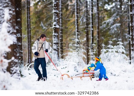 Father and kids enjoy a sleigh ride in winter forest. Baby boy and toddler girl sled in snowy park. Dad pulling children on sledge. Parent and child sledding. Family outdoor fun on Christmas vacation