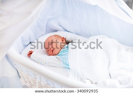 Newborn baby boy in bed. New born child sleeping under a white knitted blanket. Children sleep. Bedding for kids. Infant napping in bed. Healthy little kid shortly after birth. Cable knit textile.