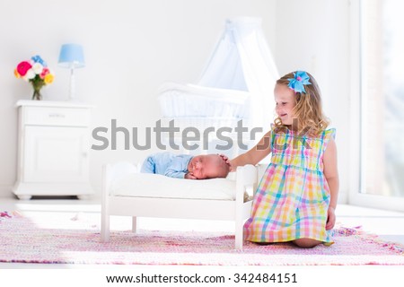 Cute little girl kissing newborn brother. Toddler kid meeting new born sibling. Infant sleeping in toy bed in white nursery. Kids playing. Siblings with small age difference. Children play and bond.