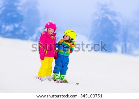 Children skiing in the mountains. Toddler kids in colorful suit and safety helmet learning to ski. Winter sport for family with young child. Kid ski lesson in alpine school. Snow fun for little skier.