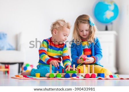 Children playing with wooden train. Toddler kid and baby play with blocks, trains and cars. Educational toys for preschool and kindergarten child. Boy and girl build toy railroad at home or daycare.