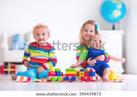 Children playing with wooden train. Toddler kid and baby play with blocks, trains and cars. Educational toys for preschool and kindergarten child. Boy and girl build toy railroad at home or daycare.
