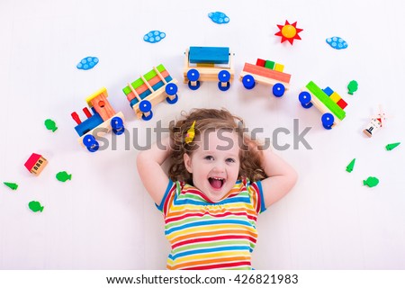 Child playing with wooden train. Toy railroad for kids. Toddler kid at day care. Educational toys for preschool and kindergarten child. Little girl at daycare.