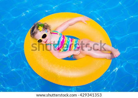 Little girl playing in outdoor swimming pool in tropical resort. Child learning to swim. Toddler kid with inflatable toy ring. Summer beach vacation for family with children. Water fun for kids.
