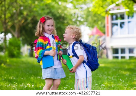 Child going to school. Boy and girl holding books and pencils on the first school day. Little students excited to be back to school. Beginning of class after vacation. Kids eating apple in school yard