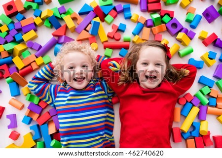 Happy preschool age children play with colorful plastic toy blocks. Creative kindergarten kids build a block tower. Educational toys for toddler or baby. Top view from above.