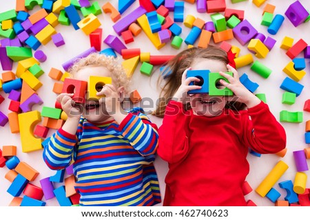 Happy preschool age children play with colorful plastic toy blocks. Creative kindergarten kids build a block tower. Educational toys for toddler or baby. Top view from above.