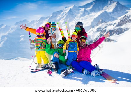 Family ski vacation. Group of skiers in Swiss Alps mountains. Adults and young children, teenager and baby skiing in winter. Parents teach kids alpine downhill skiing. Ski gear and wear, safe helmets.