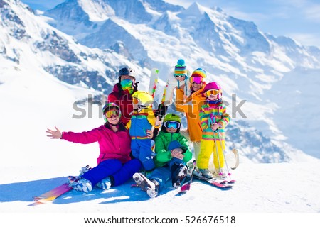 Family ski vacation. Group of skiers in Swiss Alps mountains. Adults and young children, teenager and baby skiing in winter. Parents teach kids alpine downhill skiing. Ski gear and wear, safe helmets.