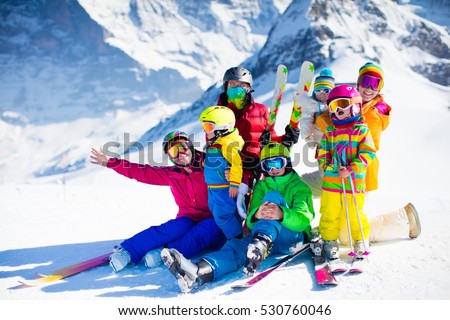 Family ski vacation. Group of skiers in Swiss Alps mountains. Adults and young children, teenager and baby skiing in winter. Parents teach kids alpine downhill skiing. Ski gear and wear, safe helmets