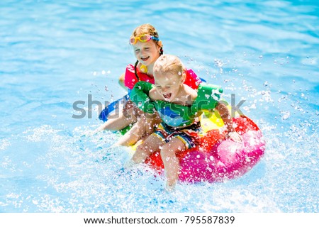 Boy and girl on inflatable ice cream float in outdoor swimming pool of tropical resort. Summer vacation with kids. Swim aids and wear for children. Water toys. Little child floating on colorful raft.