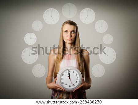 Girl holding clock in her hands. Time concept. Several minutes to twelve.