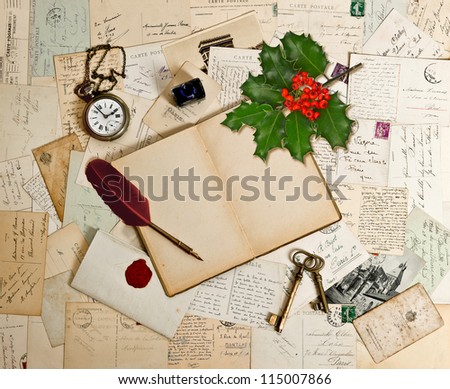 empty open book, old accessories, post cards and holly berry. romantic vintage background