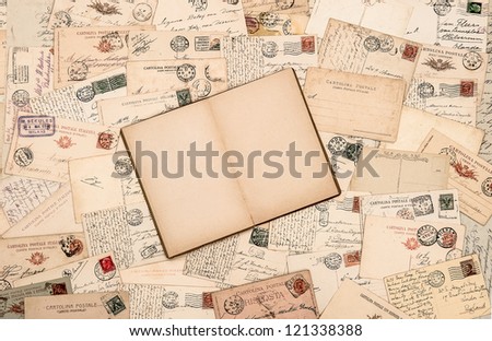 nostalgic vintage background with old handwritten postcards and open empty book page