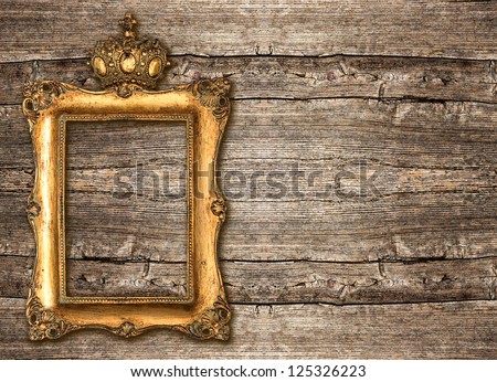 golden frame with crown over rustic wooden background