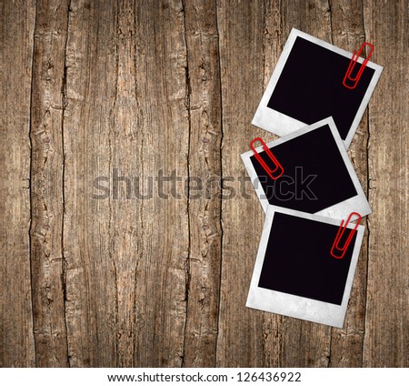 three old photo frames with red clips over rustic wooden background