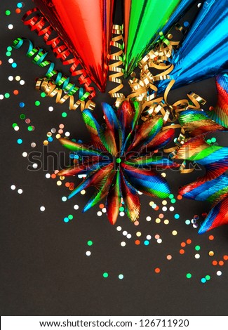 festive carnival decoration with colorful garlands, streamer, party hats and confetti on black background