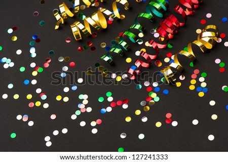 colorful streamer and confetti on black paper background. party decoration