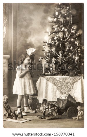 BERLIN, GERMANY - CIRCA 1900: antique photo of little girl with christmas tree and vintage toys, circa 1900 in Berlin, Germany
