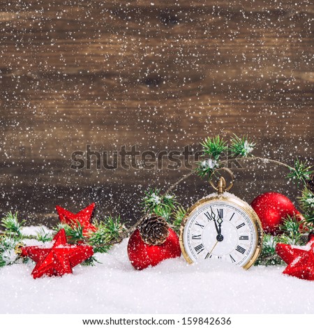christmas decoration red stars and baubles and antique golden clock in snow over wooden background. vintage style picture with falling snow effect