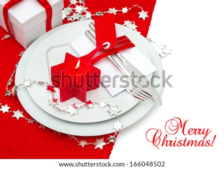 festive christmas table place setting decoration in red and silver. candle light dinner. holidays background with sample text Merry Christmas!