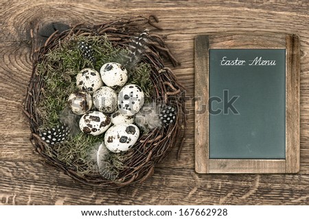 birds eggs in nest on rustic wooden background. vintage easter decoration with blackboard and sample text Easter Menu