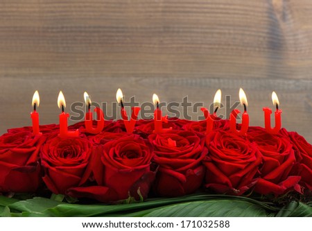 red roses and burning candles making I LOVE YOU. flower arrangement