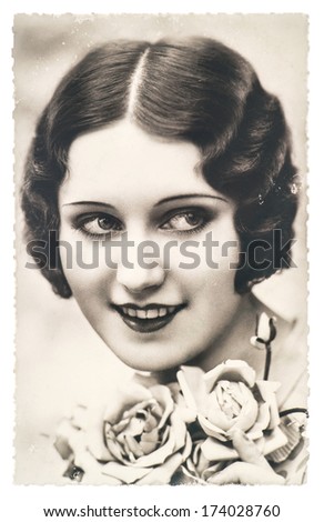 FRANCE, PARIS - CIRCA 1920: portrait of young woman with rose flowers. Retro style make up and hair look